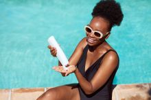 Black woman applying sunscreen in pool