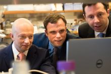three men looking at a computer